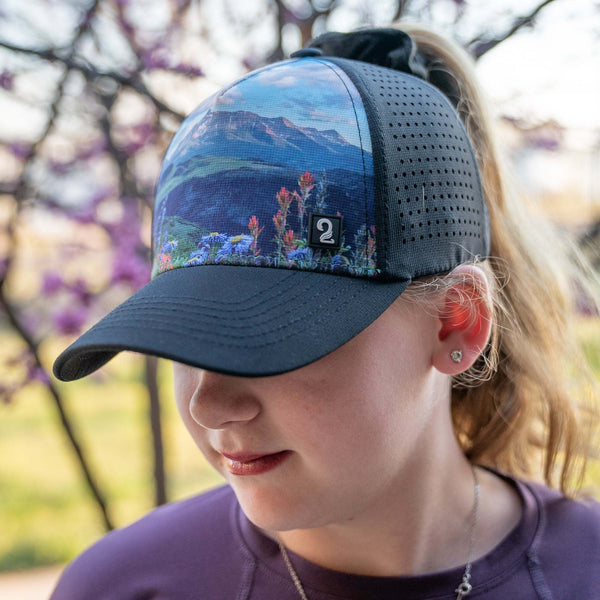 Youth Girls Trucker Hat with high ponytail opening featuring mountain landscape design, water-resistant and breathable for outdoor adventures