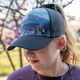 Youth Girls Trucker Hat with high ponytail opening featuring mountain landscape design, water-resistant and breathable for outdoor adventures