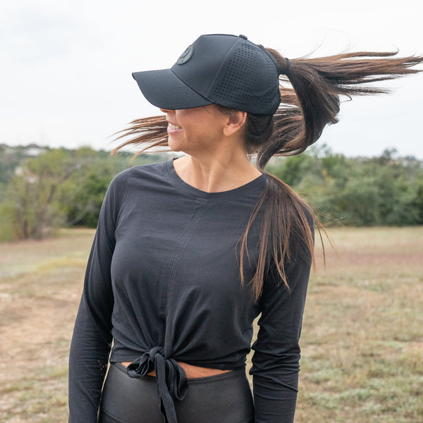 Woman wearing black ponytail hat outdoors with high ponytail opening and breathable design