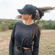Woman wearing black ponytail hat outdoors with high ponytail opening and breathable design