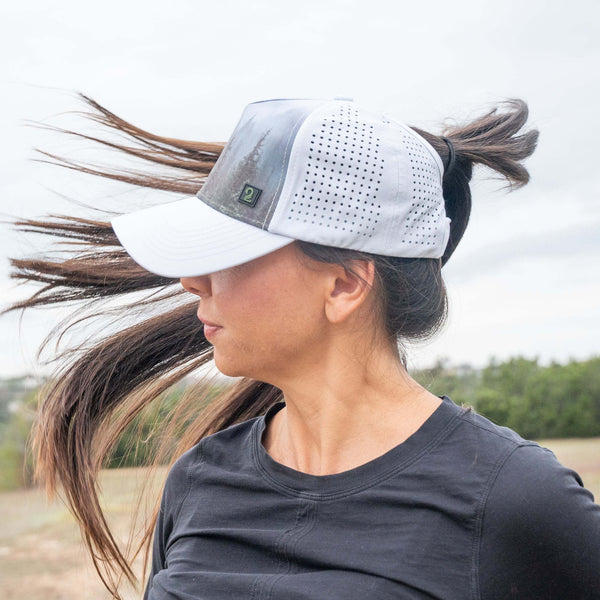 Female wearing a high ponytail womens trucker hat with breathable, water-resistant material outdoors