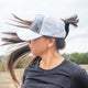 Female wearing a high ponytail womens trucker hat with breathable, water-resistant material outdoors