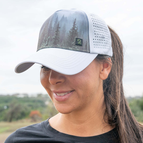 Woman wearing white high ponytail womens trucker hat with forest design and moisture-wicking breathable fabric