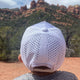 Youth Performance Boys Trucker Hat with breathable, water-resistant material and high ponytail opening in outdoor mountain setting