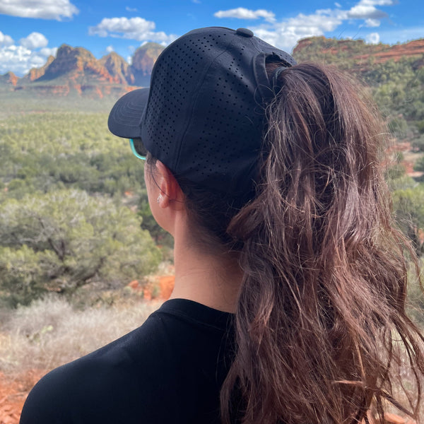 Woman wearing black high ponytail hat with breathable design outdoors in desert landscape