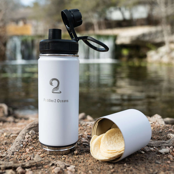 White insulated kids water bottle with detachable storage compartment holding snacks outdoors near a waterfall